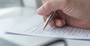 hand holding pen filling out application form